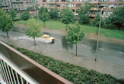 831075 Afbeelding van een auto die door de waterplassen heenrijdt in een ondergelopen Tigrisdreef te Utrecht.